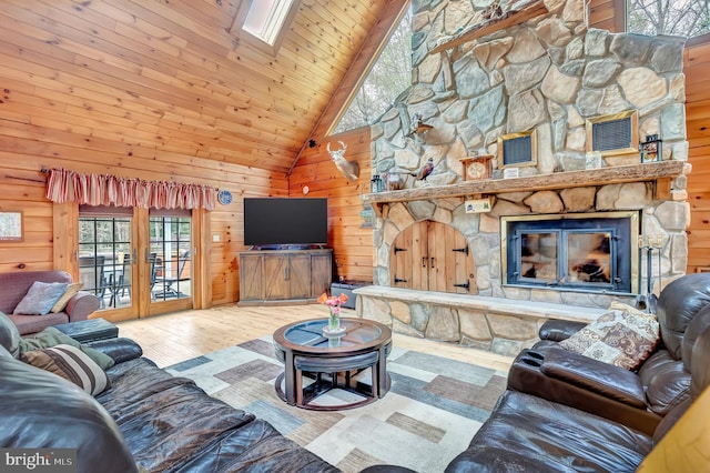 living room featuring wood ceiling, wood walls, wood finished floors, high vaulted ceiling, and a stone fireplace