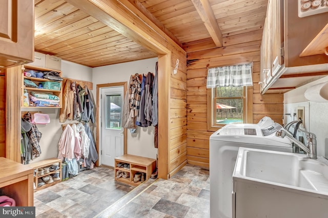 laundry room with wood ceiling, stone finish flooring, wooden walls, washer and dryer, and cabinet space