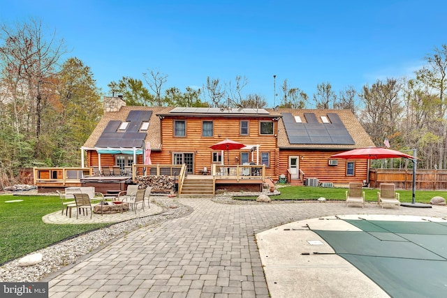 rear view of property with a shingled roof, a patio area, an outdoor fire pit, a fenced in pool, and a deck