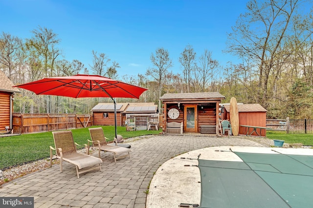 view of patio / terrace with an outdoor structure, a storage unit, and a fenced backyard