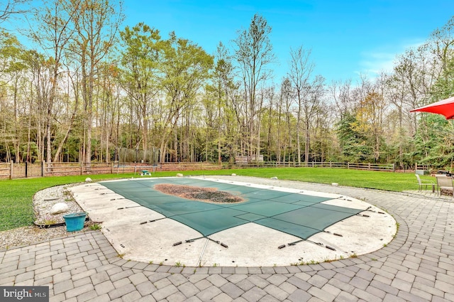 view of swimming pool featuring a yard, a covered pool, a fenced backyard, and a patio area