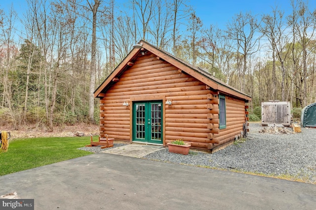 view of outdoor structure with french doors, an outdoor structure, and a forest view