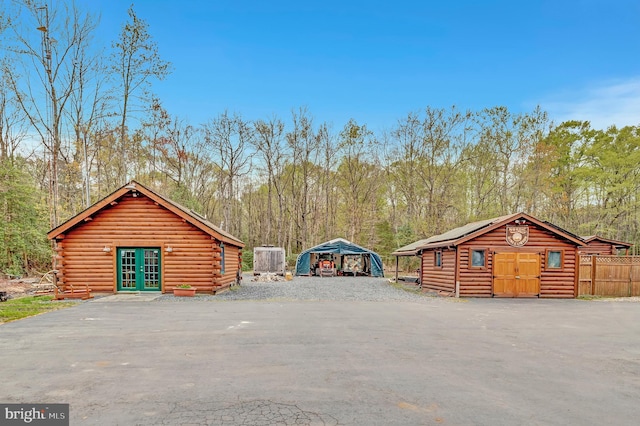 garage with driveway, a detached carport, french doors, and a forest view