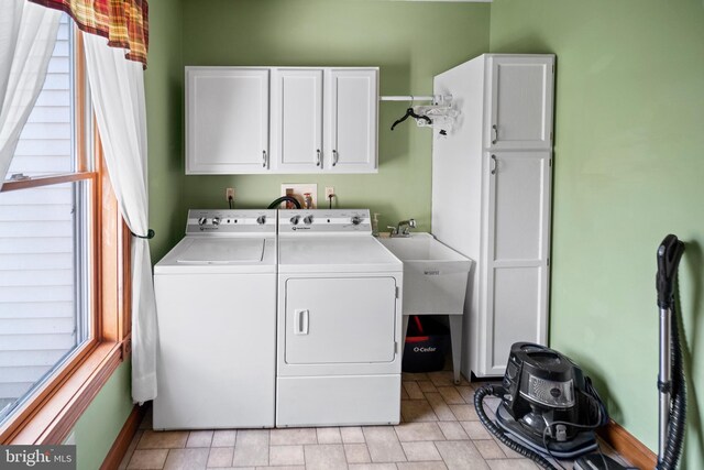 laundry room with a sink, cabinet space, stone finish flooring, baseboards, and washer and dryer