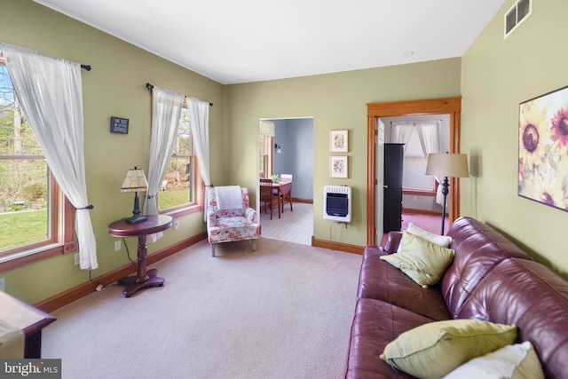 living room with heating unit, visible vents, carpet, and baseboards