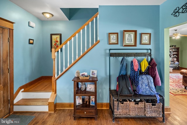 interior space featuring wood finished floors, ceiling fan, baseboards, and stairs