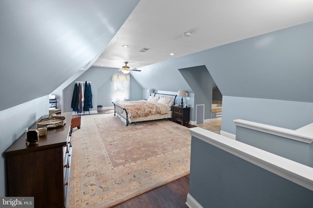 bedroom with wood finished floors, visible vents, vaulted ceiling, and baseboards