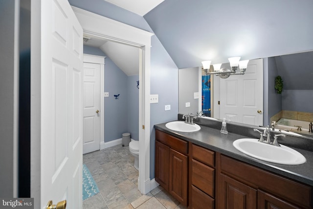 full bathroom with double vanity, toilet, lofted ceiling, and a sink