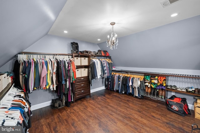 spacious closet featuring lofted ceiling, wood finished floors, visible vents, and an inviting chandelier