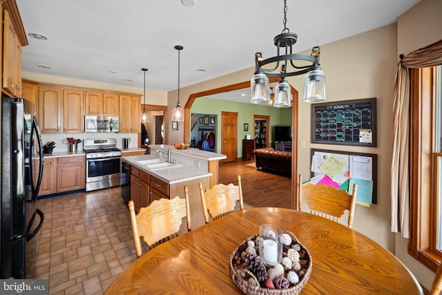 kitchen featuring a sink, light countertops, black appliances, open floor plan, and a center island with sink