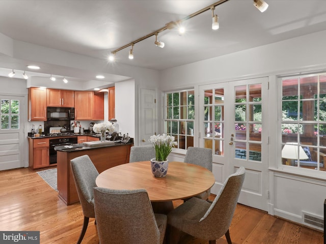 dining space with light wood finished floors, track lighting, and visible vents
