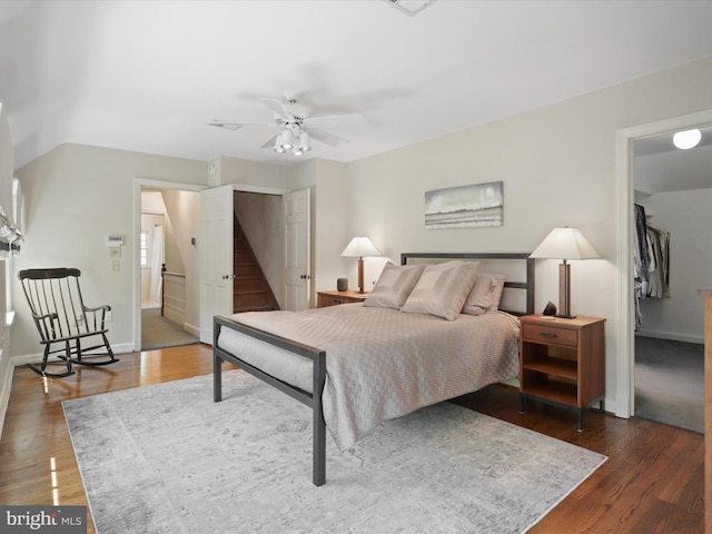 bedroom featuring a ceiling fan, a closet, baseboards, a spacious closet, and dark wood-style floors