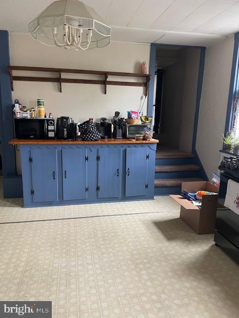 interior space with open shelves, black microwave, wooden counters, an inviting chandelier, and blue cabinetry