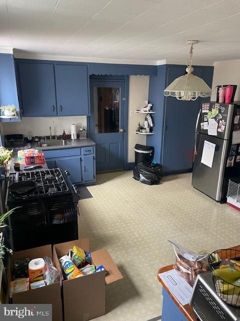 kitchen with a chandelier, blue cabinets, freestanding refrigerator, and a sink