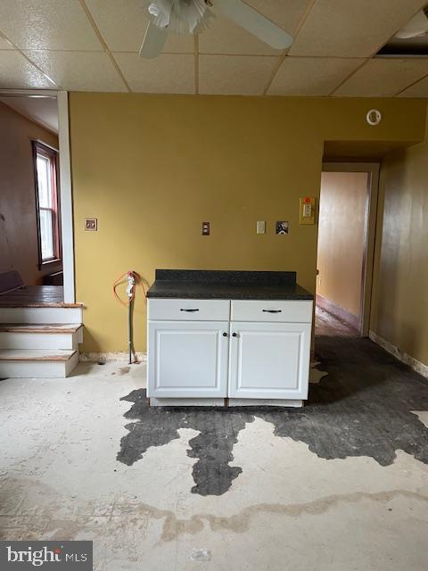 spare room featuring a ceiling fan, a drop ceiling, and baseboards