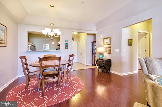 dining space with baseboards, a chandelier, and wood finished floors