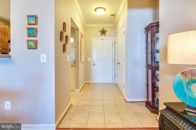 doorway featuring crown molding, baseboards, light tile patterned flooring, and visible vents