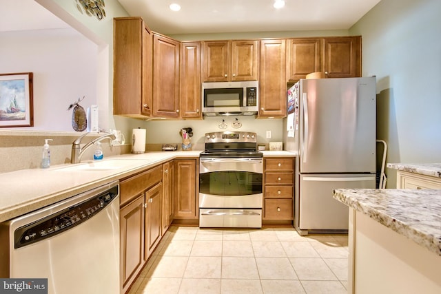 kitchen with recessed lighting, light countertops, a sink, appliances with stainless steel finishes, and light tile patterned floors