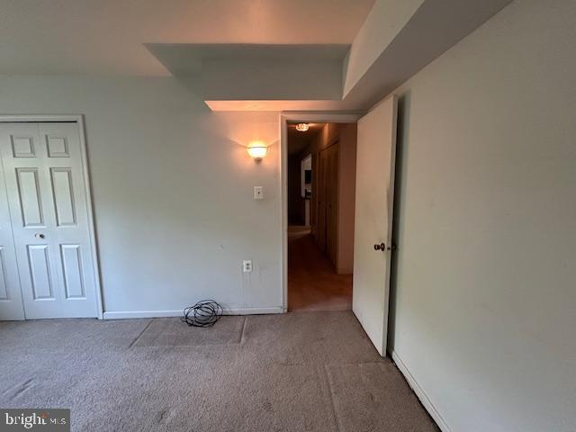 unfurnished bedroom featuring baseboards, carpet, and a closet