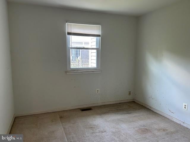 carpeted empty room featuring baseboards and visible vents