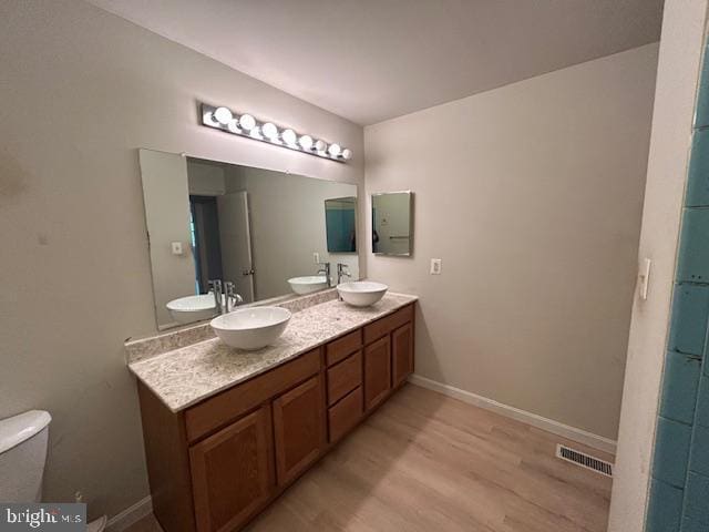 bathroom with visible vents, a sink, and wood finished floors