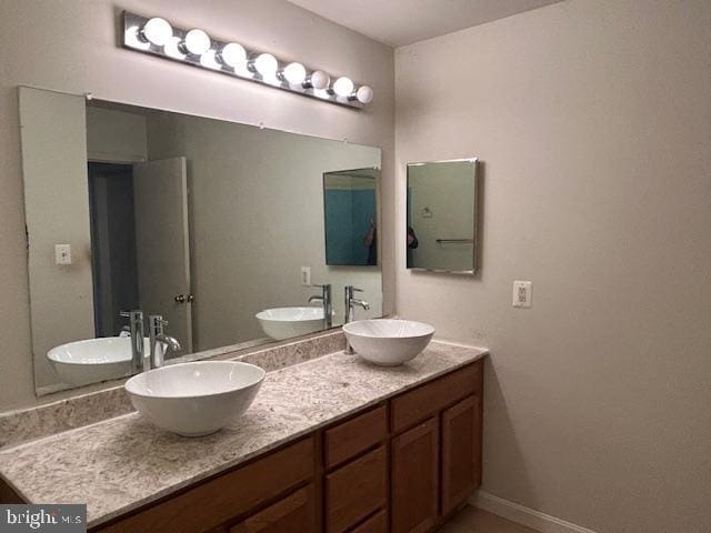 bathroom with double vanity, baseboards, and a sink