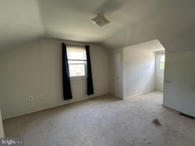 additional living space with vaulted ceiling and carpet flooring