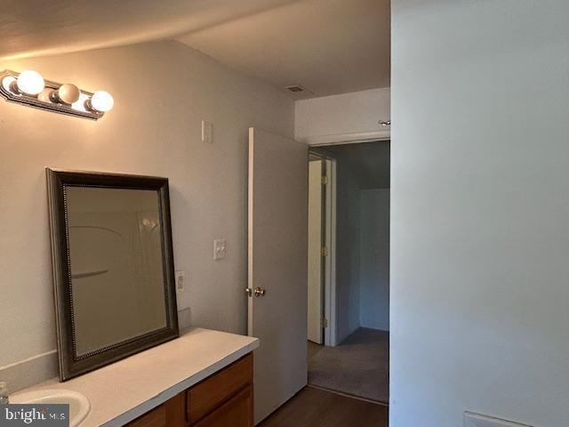 bathroom with vanity, wood finished floors, and vaulted ceiling
