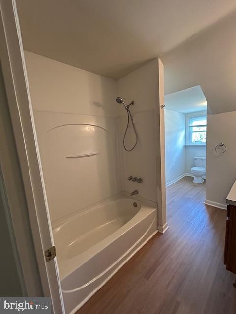 full bath with shower / tub combination, vanity, toilet, baseboards, and wood finished floors
