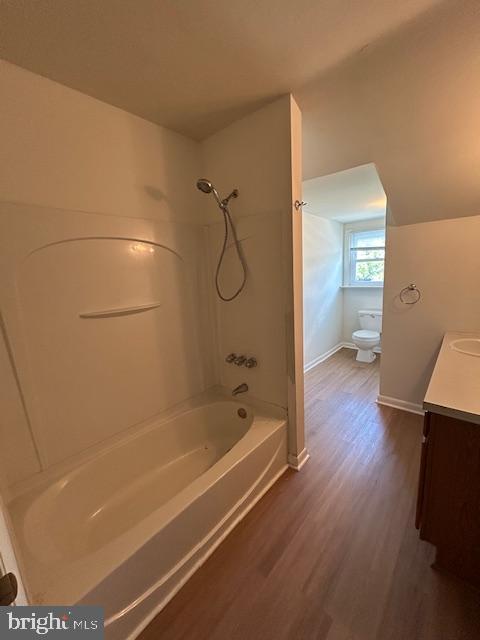 full bath featuring vanity, shower / bathtub combination, toilet, baseboards, and wood finished floors