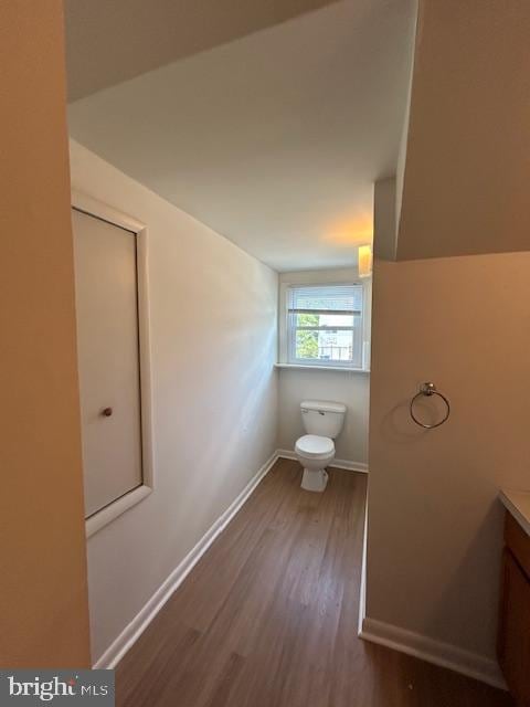 bathroom featuring vanity, baseboards, wood finished floors, and toilet