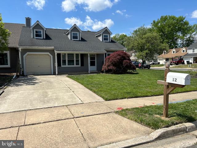 cape cod home with concrete driveway, an attached garage, a chimney, and a front yard