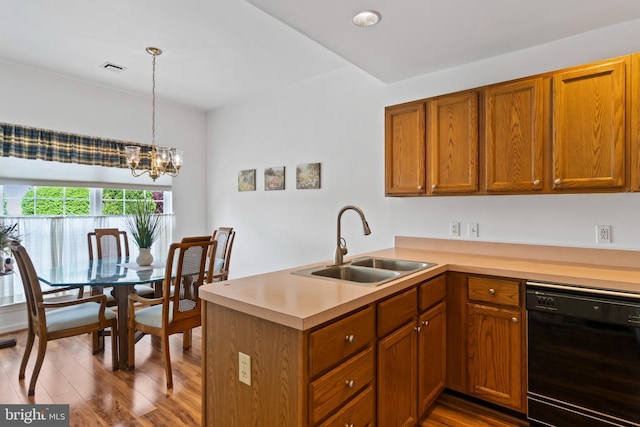 kitchen with wood finished floors, a sink, light countertops, a peninsula, and black dishwasher