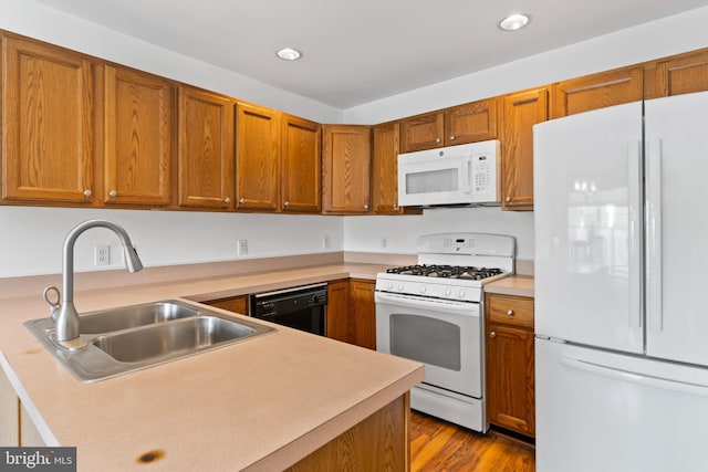 kitchen with recessed lighting, light countertops, a sink, and white appliances