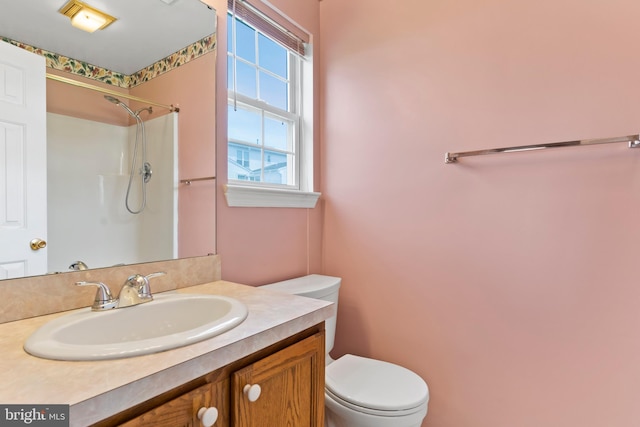 bathroom with vanity, a shower, and toilet