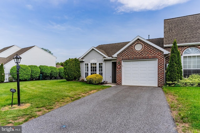 ranch-style home with brick siding, aphalt driveway, an attached garage, a shingled roof, and a front lawn