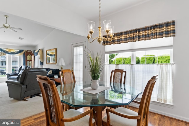 dining space with visible vents, ceiling fan with notable chandelier, wood finished floors, and vaulted ceiling