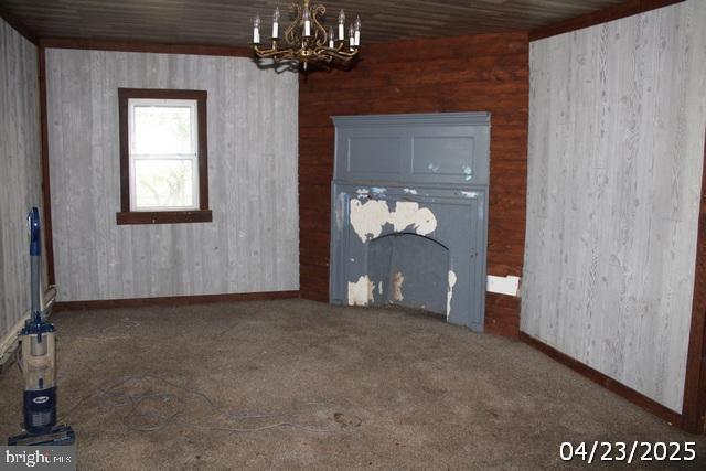 9635 Upper Strasburg Rd, Upperstrasburg, PA 17265 - carpeted spare room with wood walls, a notable chandelier, and baseboards