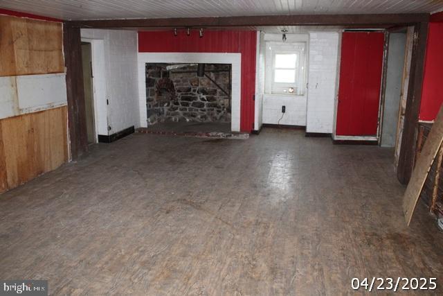 9635 Upper Strasburg Rd, Upperstrasburg, PA 17265 - unfurnished living room featuring a fireplace with raised hearth, wood walls, and wood finished floors