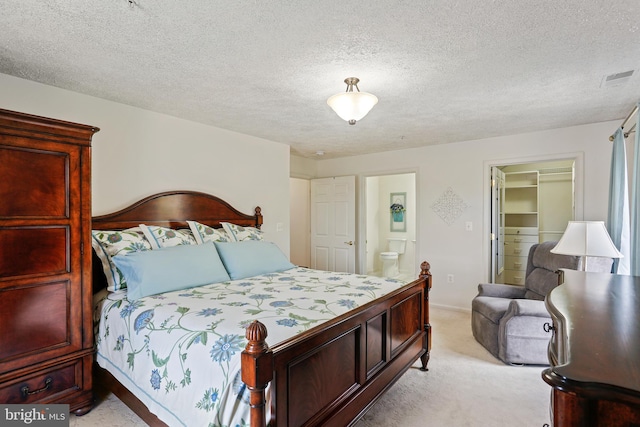 bedroom featuring light colored carpet, visible vents, and a textured ceiling