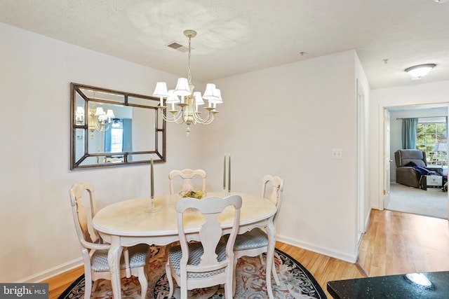 dining area with visible vents, a notable chandelier, wood finished floors, and baseboards
