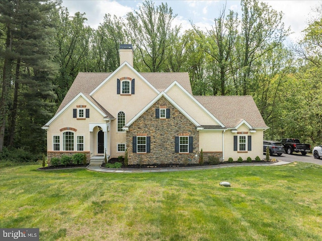view of front of property featuring a chimney, a front lawn, stucco siding, and stone siding