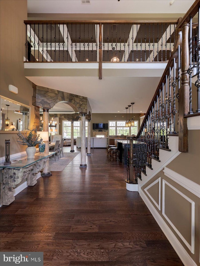 entryway featuring ornate columns, wood finished floors, and a towering ceiling