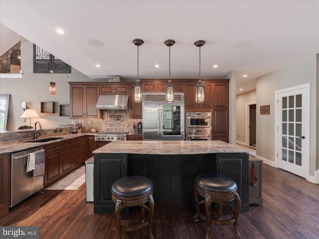kitchen featuring decorative backsplash, appliances with stainless steel finishes, a sink, under cabinet range hood, and dark wood-type flooring