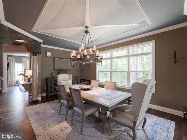 dining room featuring dark wood-style flooring, a notable chandelier, a raised ceiling, baseboards, and ornamental molding
