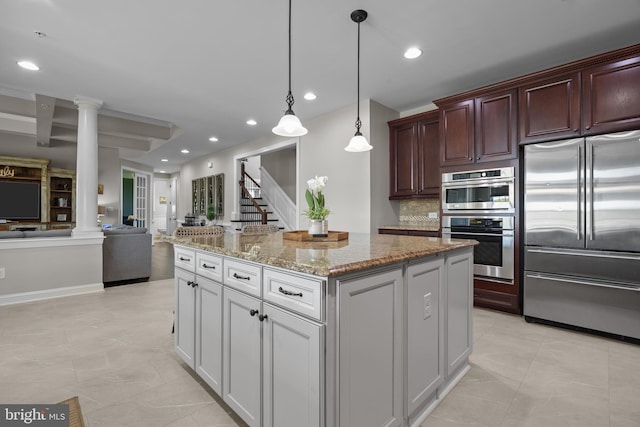 kitchen featuring decorative columns, recessed lighting, a center island, light stone counters, and appliances with stainless steel finishes