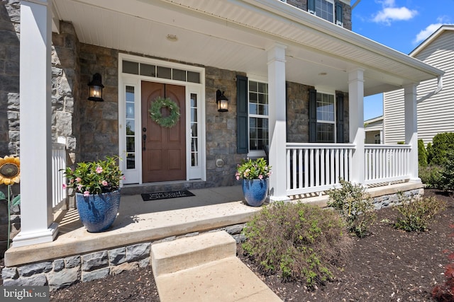 entrance to property featuring covered porch and stone siding