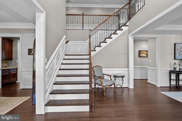 stairway featuring crown molding, wainscoting, a decorative wall, and wood finished floors