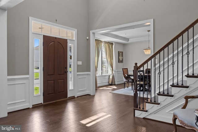entryway featuring a decorative wall, wood finished floors, stairway, and a wainscoted wall
