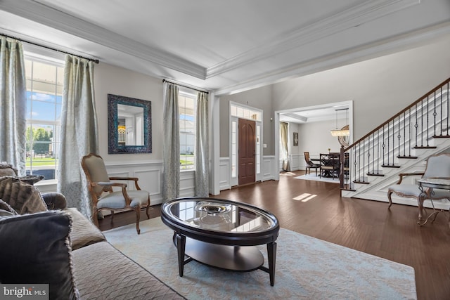 living room with ornamental molding, stairs, a decorative wall, wood finished floors, and a wainscoted wall